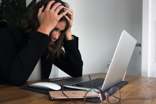 woman looking at her laptop with her hands on her head